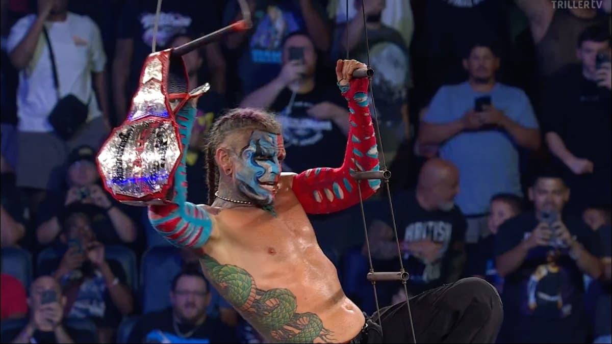 Jeff Hardy grabbing the TNA World Tag Team Titles while hanging from a ladder rope