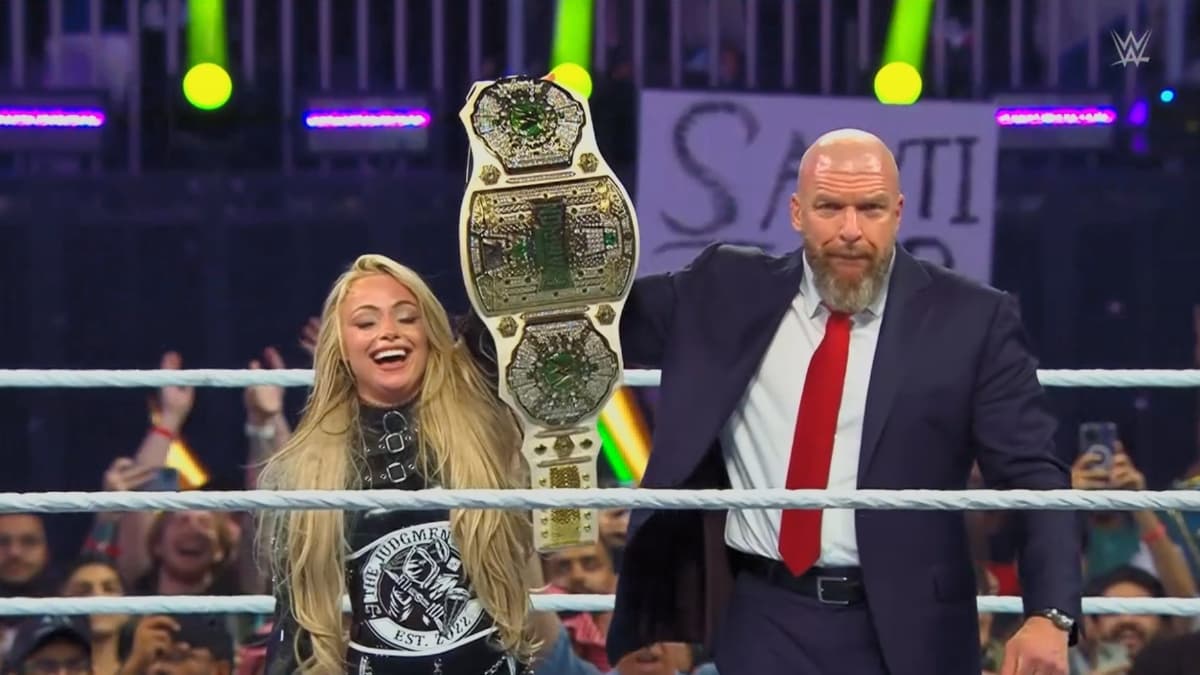 Liv Morgan celebrates in-ring with a suited Triple H as she hold up the Crown Jewel Championship